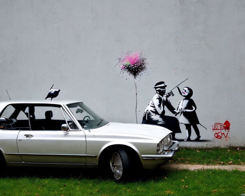 Vintage car parked in front of mural with stenciled man and girl holding heart-shaped balloon.