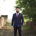 Decorated man in navy blue military uniform in ethereal garden with sunlight.