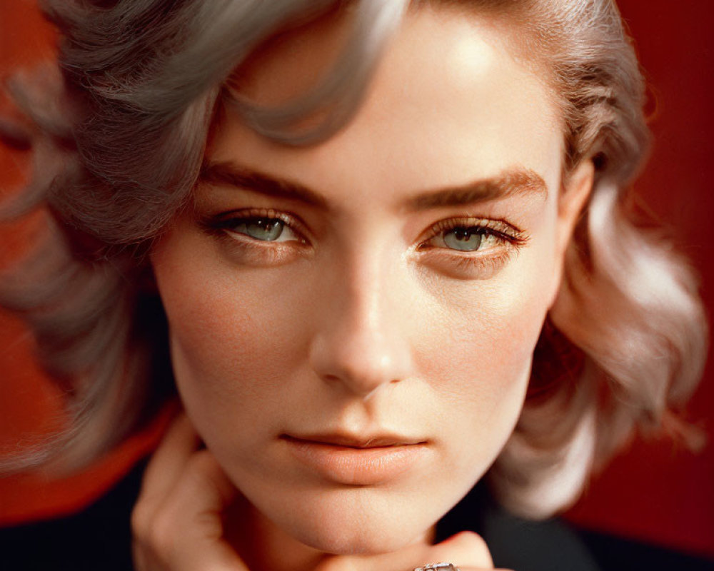 Portrait of woman with short wavy hair and striking eyes on red background