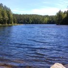 Serene Lake with Rocky Shores and Sea Serpent in Clear Sky