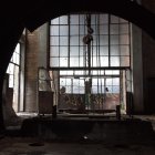 Dimly Lit Industrial Interior with Sunlight Streaming Through Large Windows