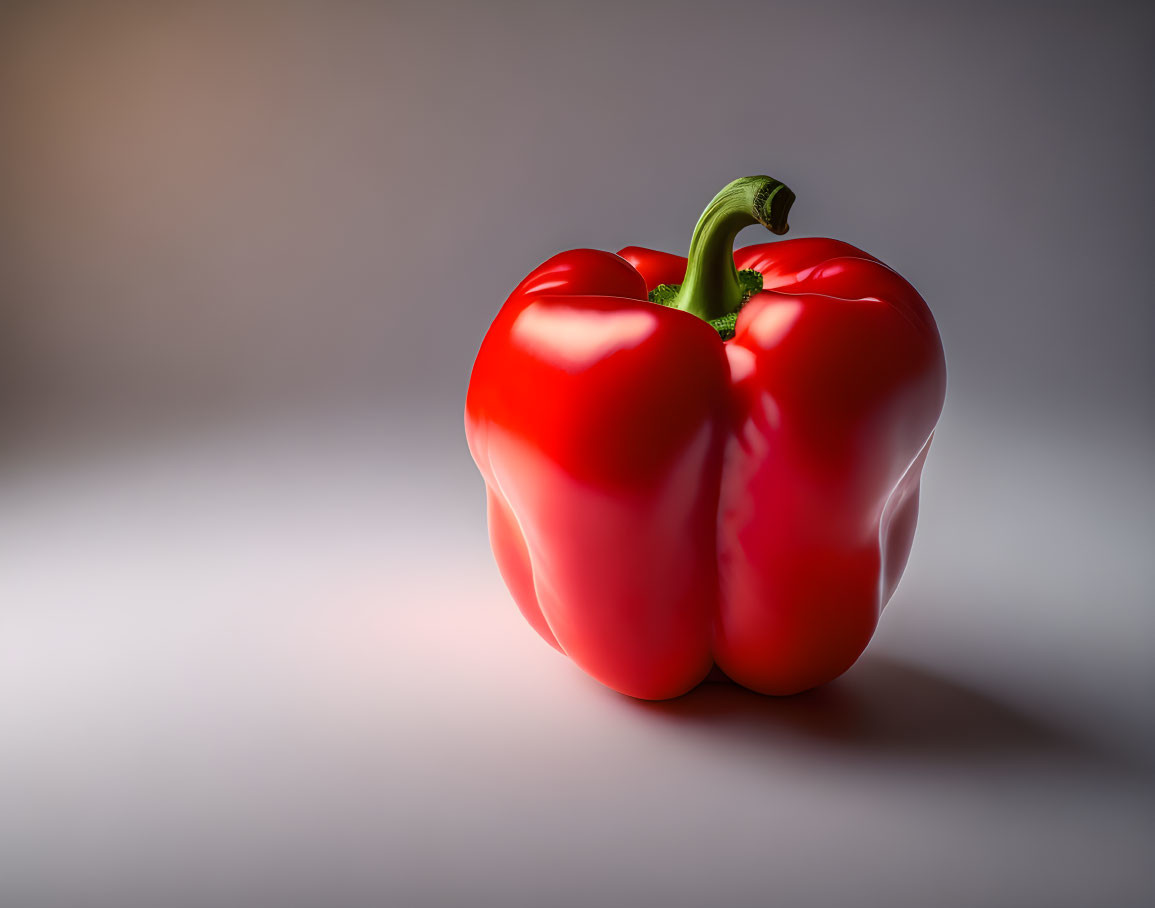 Vibrant red bell pepper with green stem on light grey background