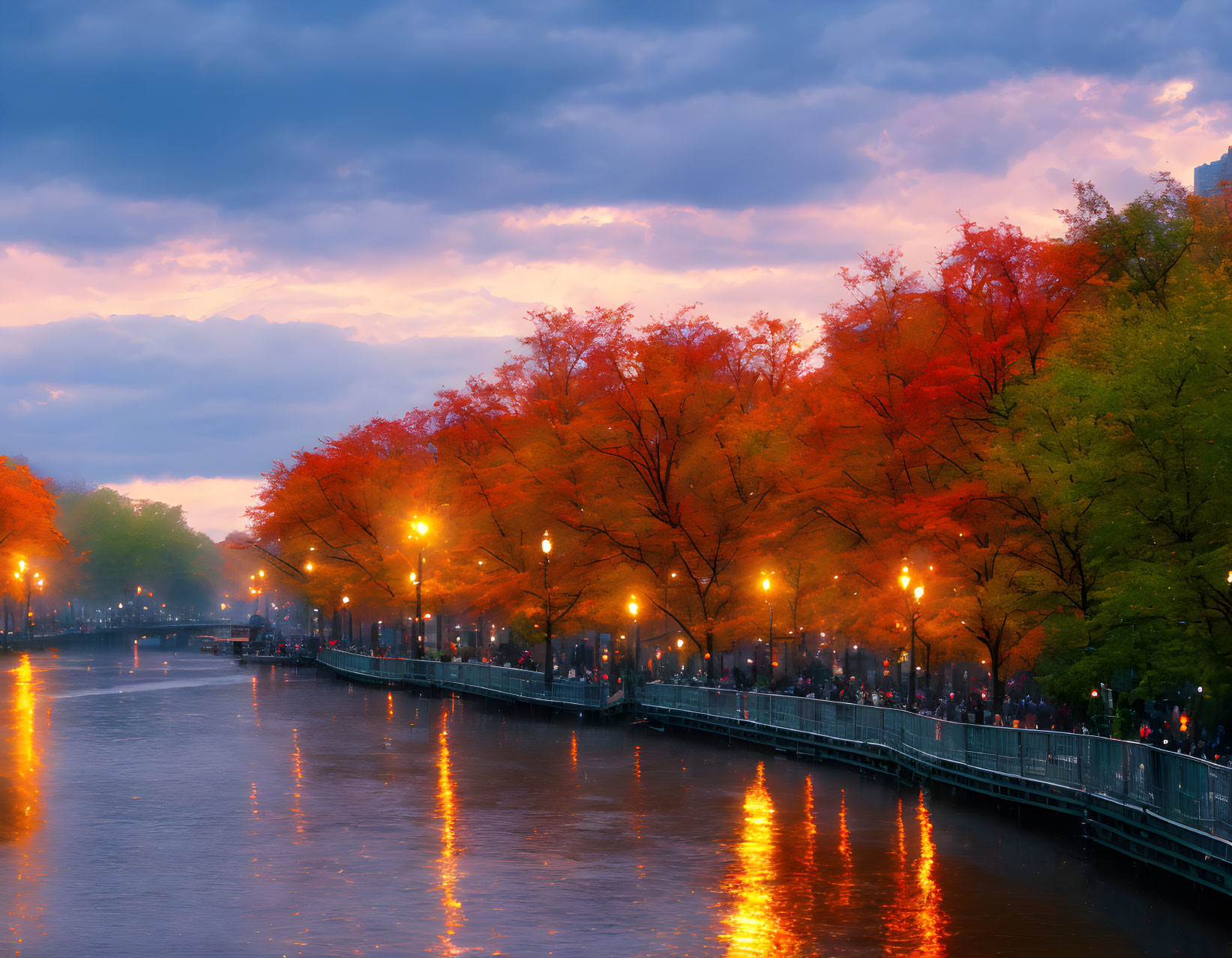 City river at twilight with glowing street lamps and autumn trees.