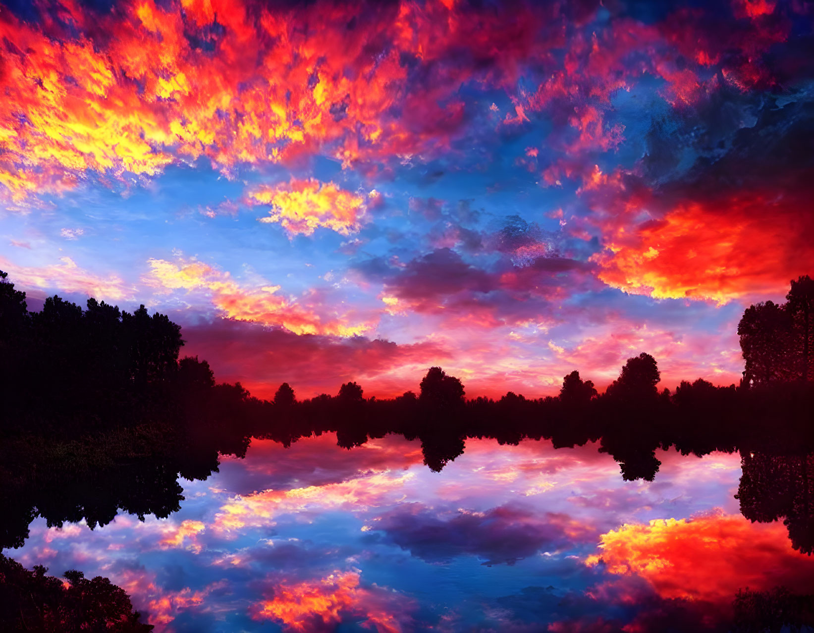 Vibrant sunset with red and blue clouds reflected in tranquil lake