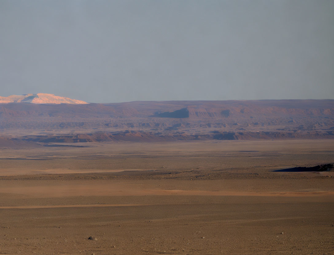 Desert landscape at dusk with distant mountains & warm glow