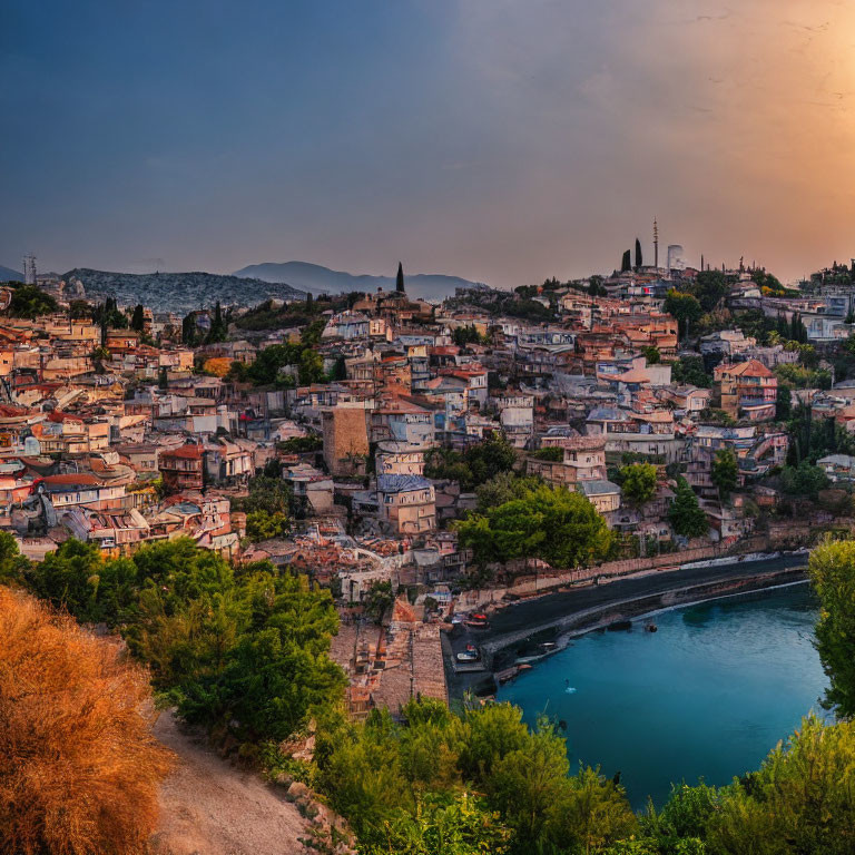 Coastal town at dusk: dense buildings, river, hills, golden sky