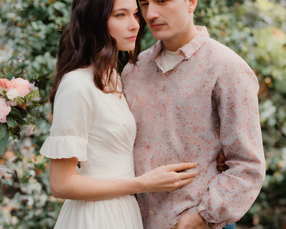 Couple in White Dress and Patterned Shirt Surrounded by Green Foliage and Pink Flowers