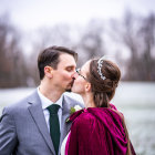 Couple kissing in elegant attire in snowy forest setting with glowing torches