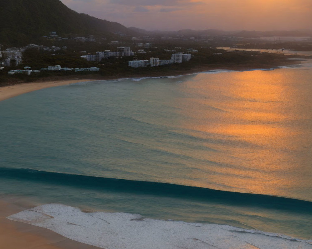 Scenic sunset over calm sea, sandy beach, mountains, and coastal buildings