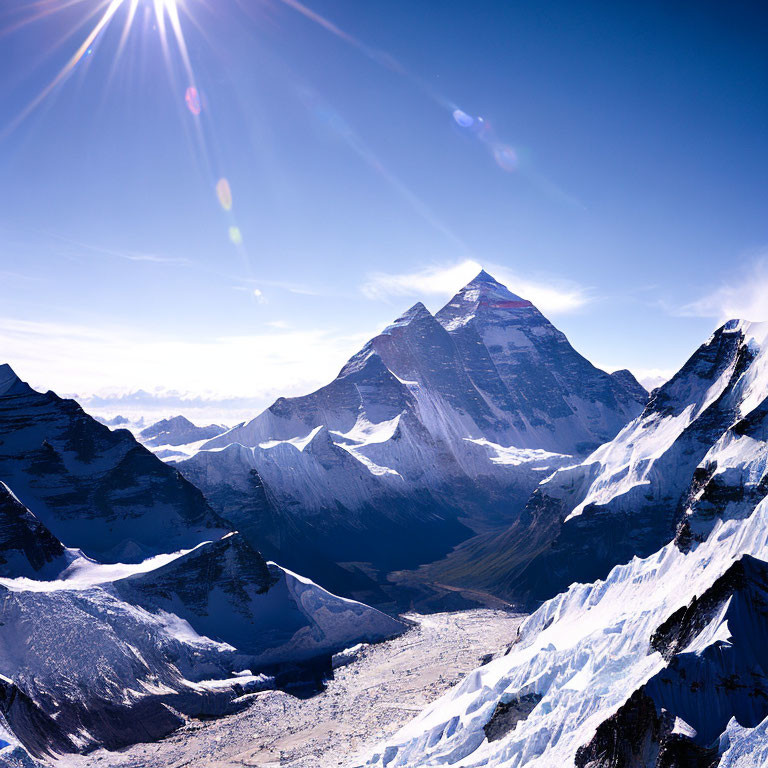 Snow-covered mountain range under sun with lens flare and clear blue skies