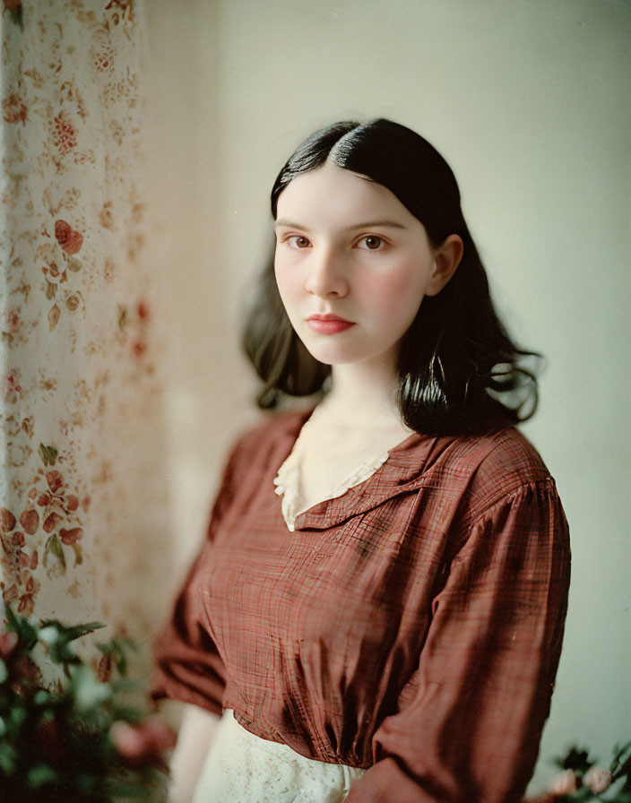 Dark-haired woman in red blouse against floral wallpaper - serene vintage look