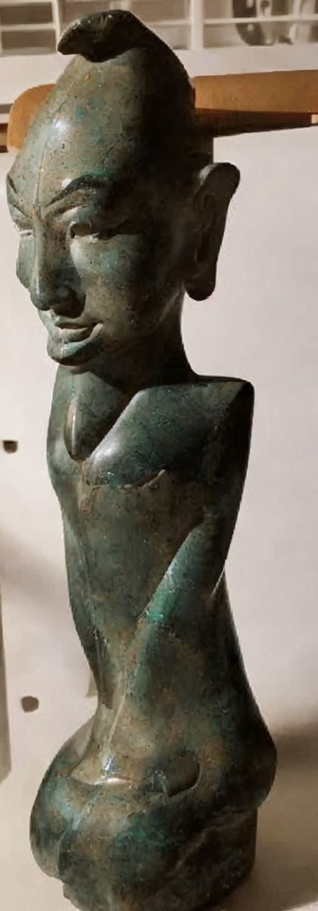 Bronze sculpture of slender figure with elongated ears and greenish patina