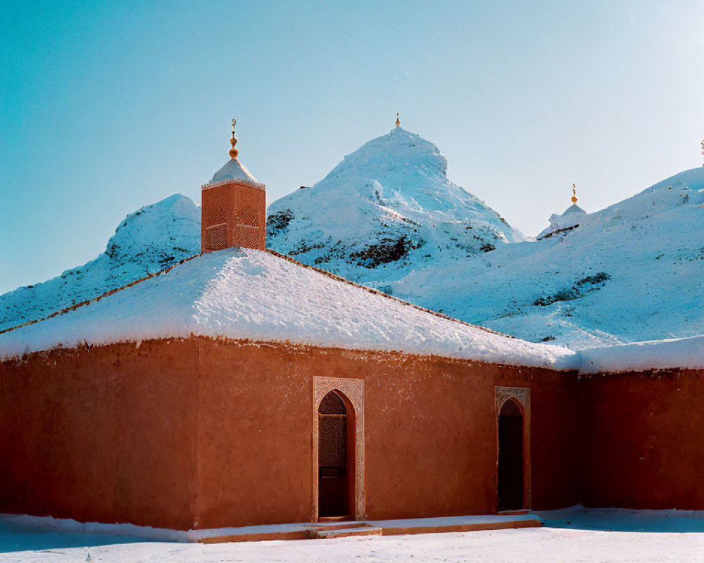 Traditional clay building with snow-capped dome and ornate tower under clear blue sky