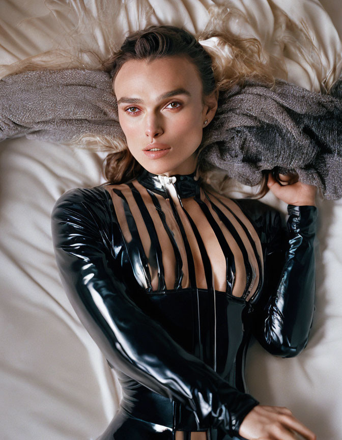 Woman in black latex bodysuit with chest cutouts on bed portrait