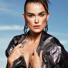 Freckled woman in metallic jacket against blue sky