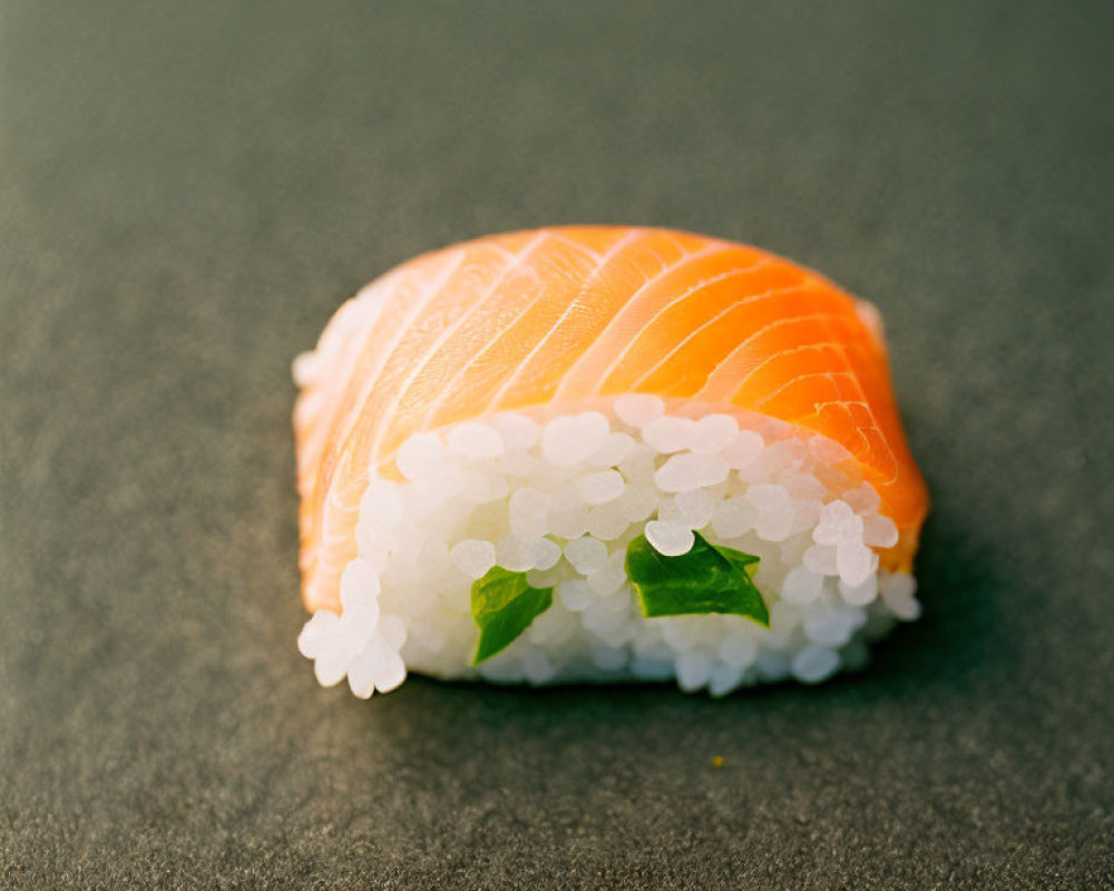 Salmon sushi on white rice with green leaves on dark background