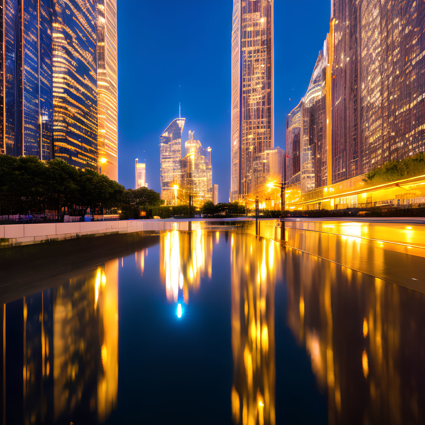 Cityscape with skyscrapers reflected in water at twilight, vibrant blue and orange lights.