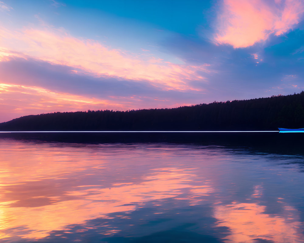 Colorful sunset over calm lake with forested horizon