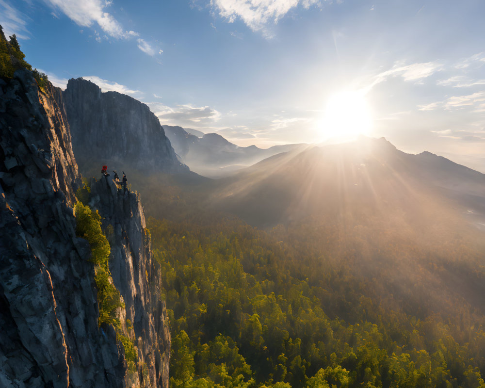 Mountain climbers at sunrise on cliff above forested valley