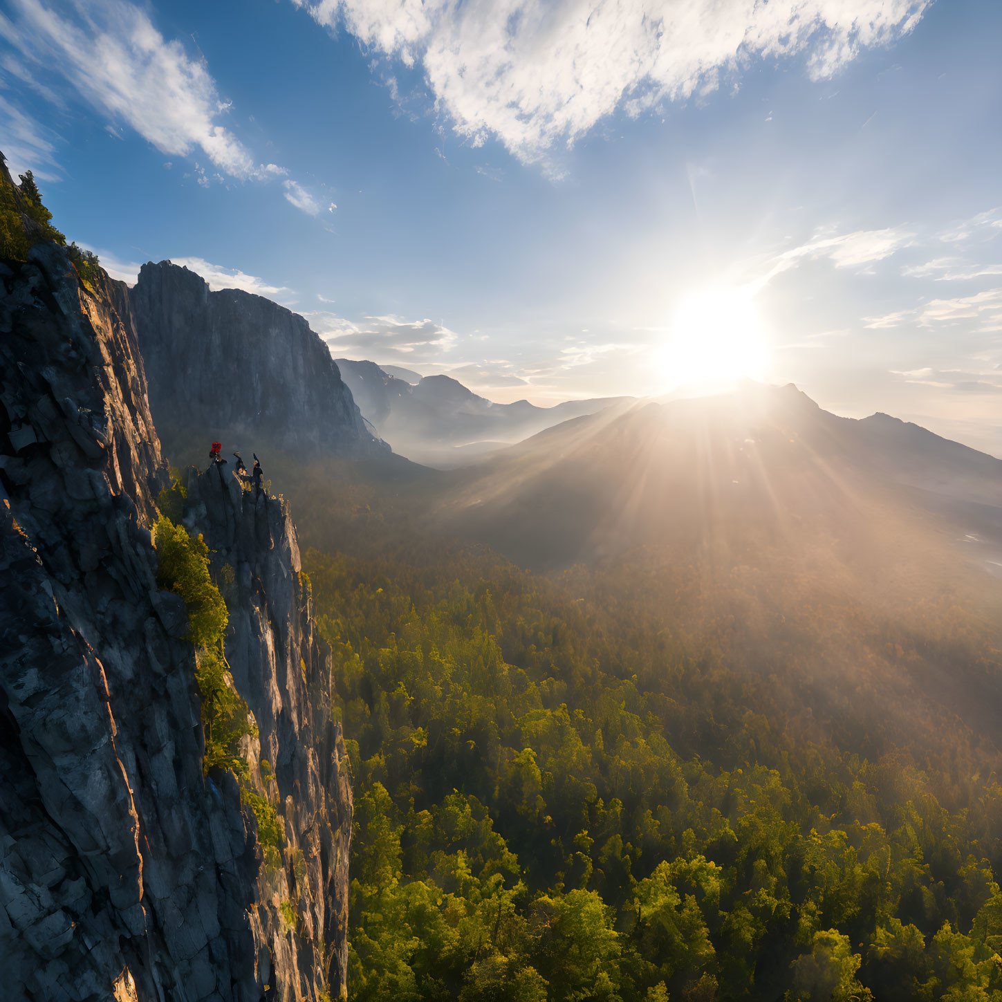 Mountain climbers at sunrise on cliff above forested valley