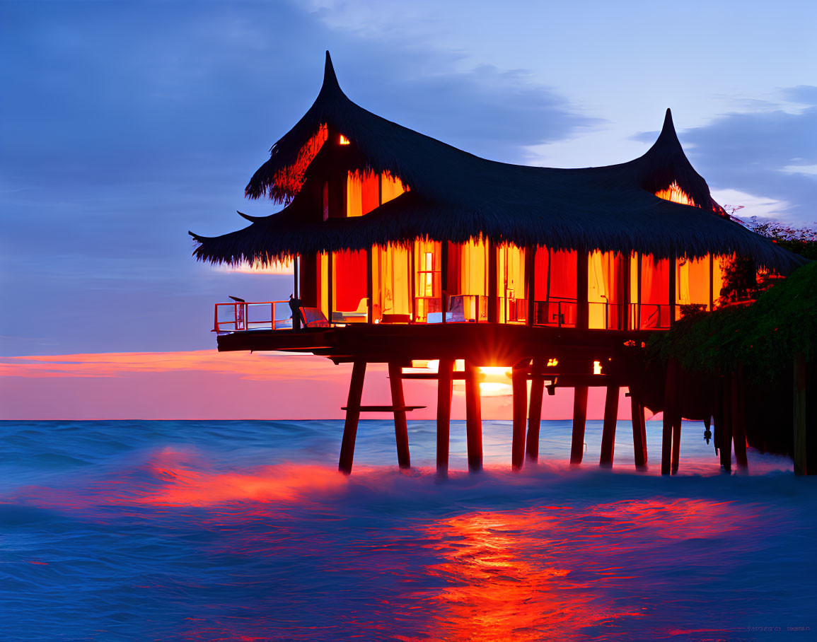 Thatched Roof Hut Over Ocean at Sunset with Orange and Blue Sky