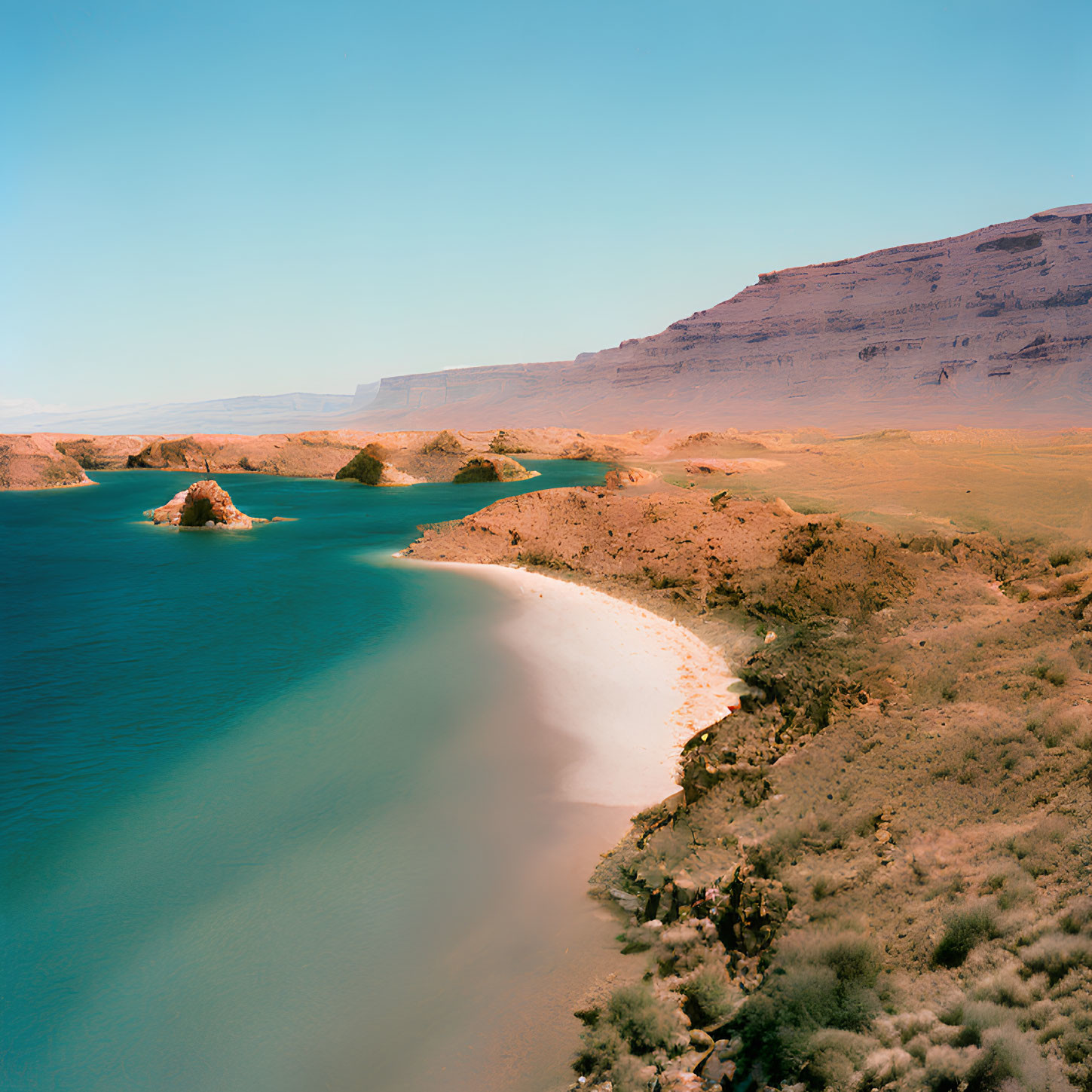 Tranquil turquoise lake with sandy beach and red cliffs