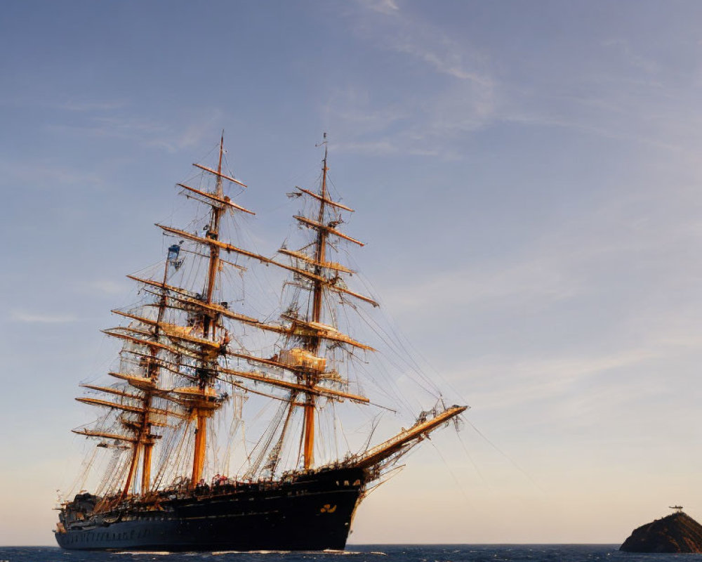 Traditional sailing ship with multiple masts and rigging on open sea at sunset