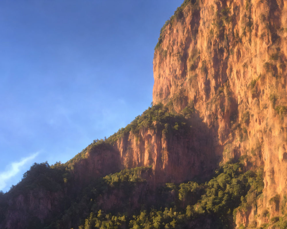 Rugged Cliff Under Clear Blue Sky with Greenery