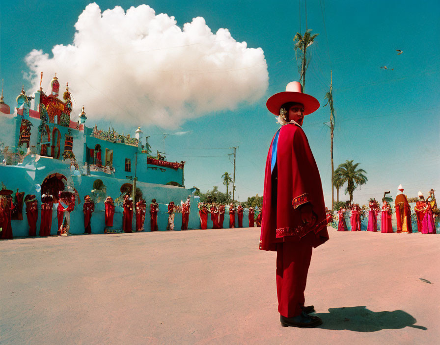 Traditional attired man with group in front of vibrant building under blue sky