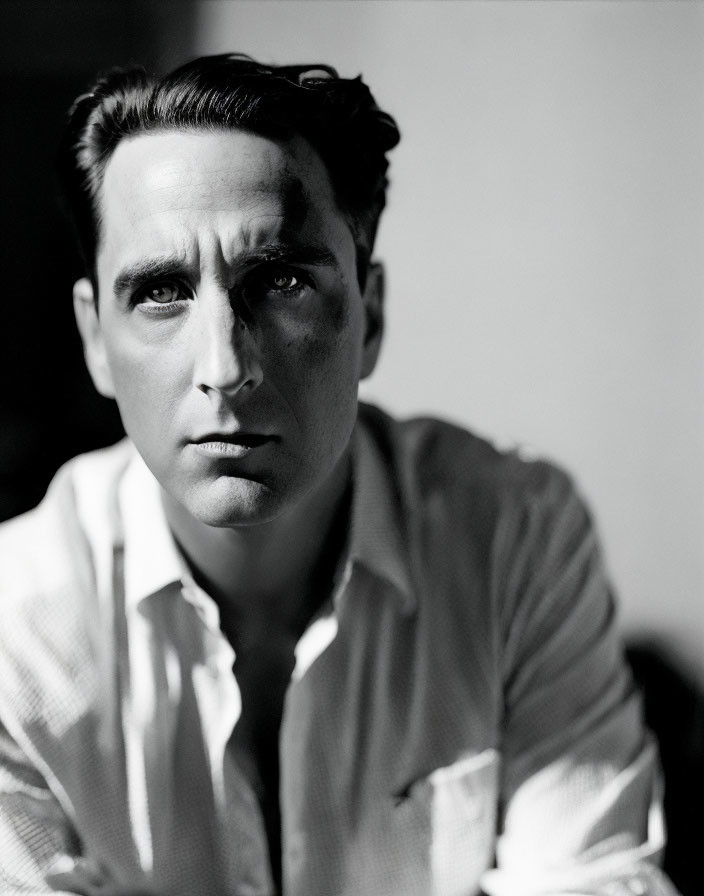 Monochrome portrait of pensive man with dark hair in white shirt