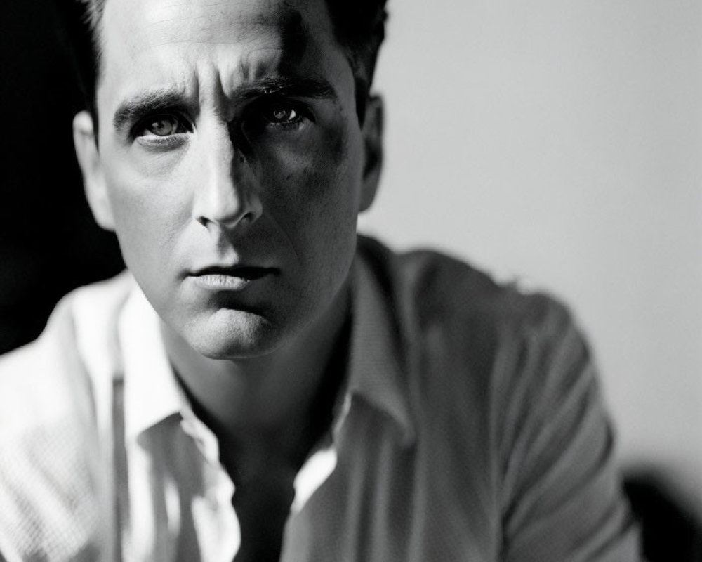 Monochrome portrait of pensive man with dark hair in white shirt