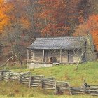 Rustic wooden cabin in autumn forest with split-rail fence