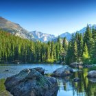 Rustic wooden cabin in lush greenery with stream and mountains