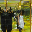 Woman walking in mirrored room with oversized black cat figures