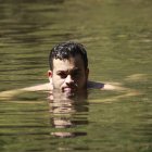 Woman with sleek hair submerged in clear water gazes at camera