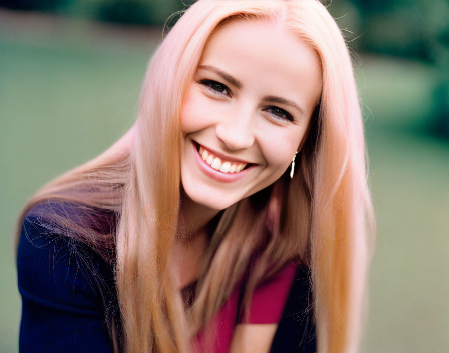 Smiling woman with long pink hair in purple top outdoors