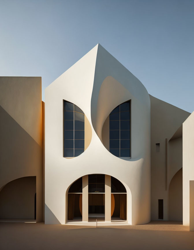 Abstract modern building with curvilinear white facades and leaf-shaped windows under clear blue sky