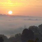 Hazy sunrise over forest with mist and soft light