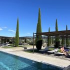 Contemporary architectural design with pointed spires, reflective pool, curved building, greenery, and blue