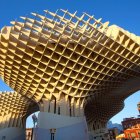 Modern building with gold honeycomb facade and white flowing supports against blue sky