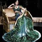 Luxurious peacock-themed gown on person sitting on white and gold sofa