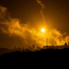 Silhouetted figures by water witness volcanic eruptions