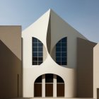 Abstract modern building with curvilinear white facades and leaf-shaped windows under clear blue sky