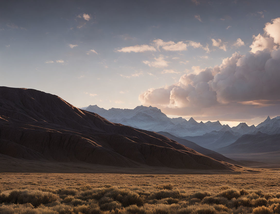 Tranquil sunset landscape with rolling hills and snowy peaks