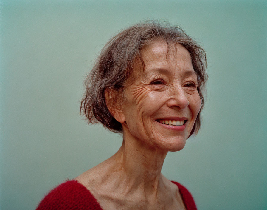 Elderly woman in red sweater with grey hair on pale blue background