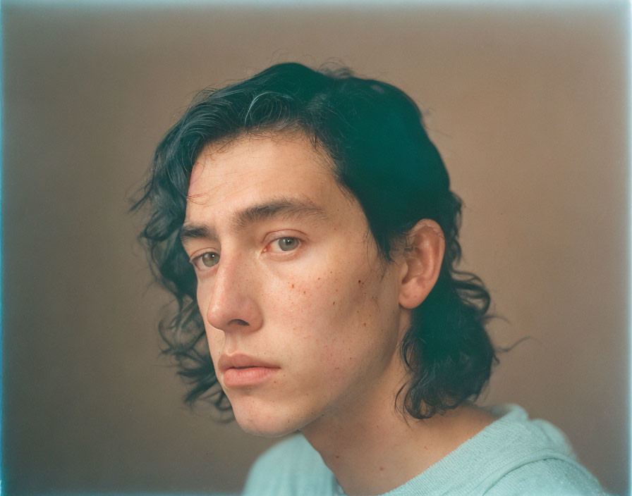 Portrait of person with shoulder-length dark hair and freckles in light blue top