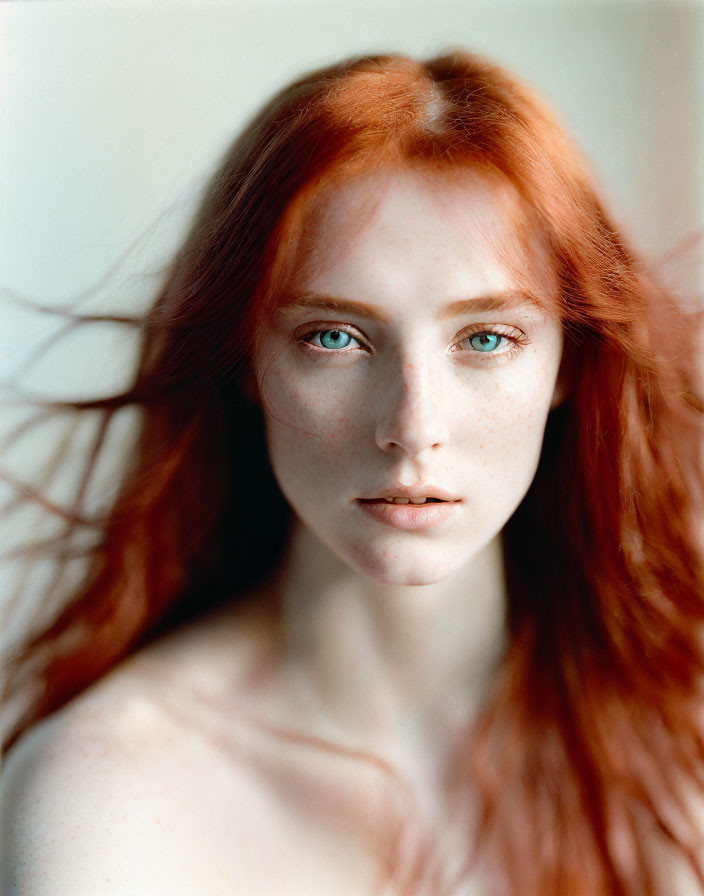 Portrait of woman with flowing red hair and striking blue eyes and freckled complexion