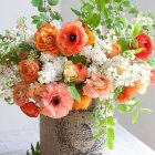 Colorful diverse flower bouquet in ornate blue vase on soft blue and white backdrop