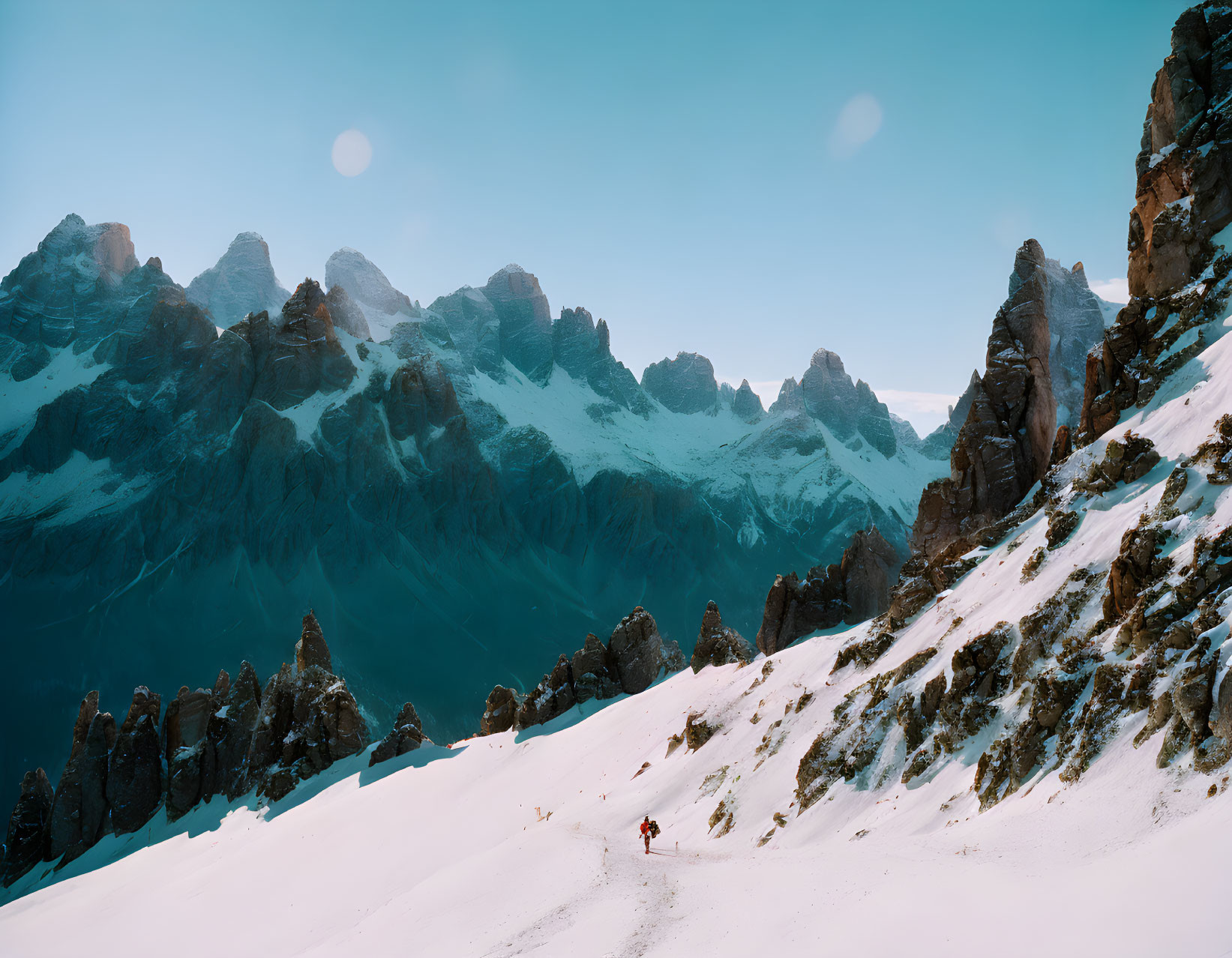 Snowy mountain pass with rocky peaks under clear blue sky