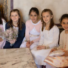 Five Women in Elegant Attire with Bouquets and Puppies Seated Among Floral Decorations